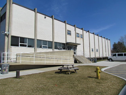 Figure 6 : Prison de Sarnia. Photo d'un bâtiment de couleur blanche. Au premier plan, une rampe d'accessibilité.