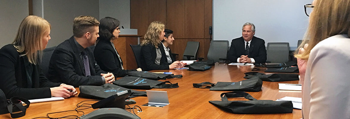 The Ombudsman, Paul Dubé, leading a board meeting with a group of 10 people surrounding him