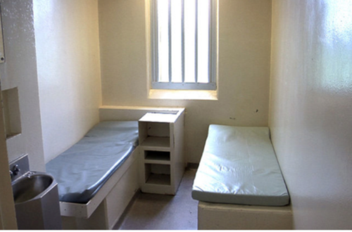 Figure 7 : Centre de détention d’<span lang=”en”>Elgin-Middlesex</span>. Photo d'une pièce comprenant deux lits individuels et une fenêtre comportant des barreaux..