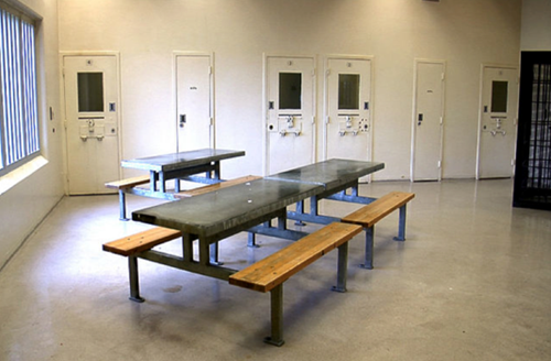 Figure 8 : Centre de détention d’<span lang=”en”>Elgin-Middlesex</span>. Photo d'une salle commune avec des bancs au premier plan et des cellules de détenus au second plan.