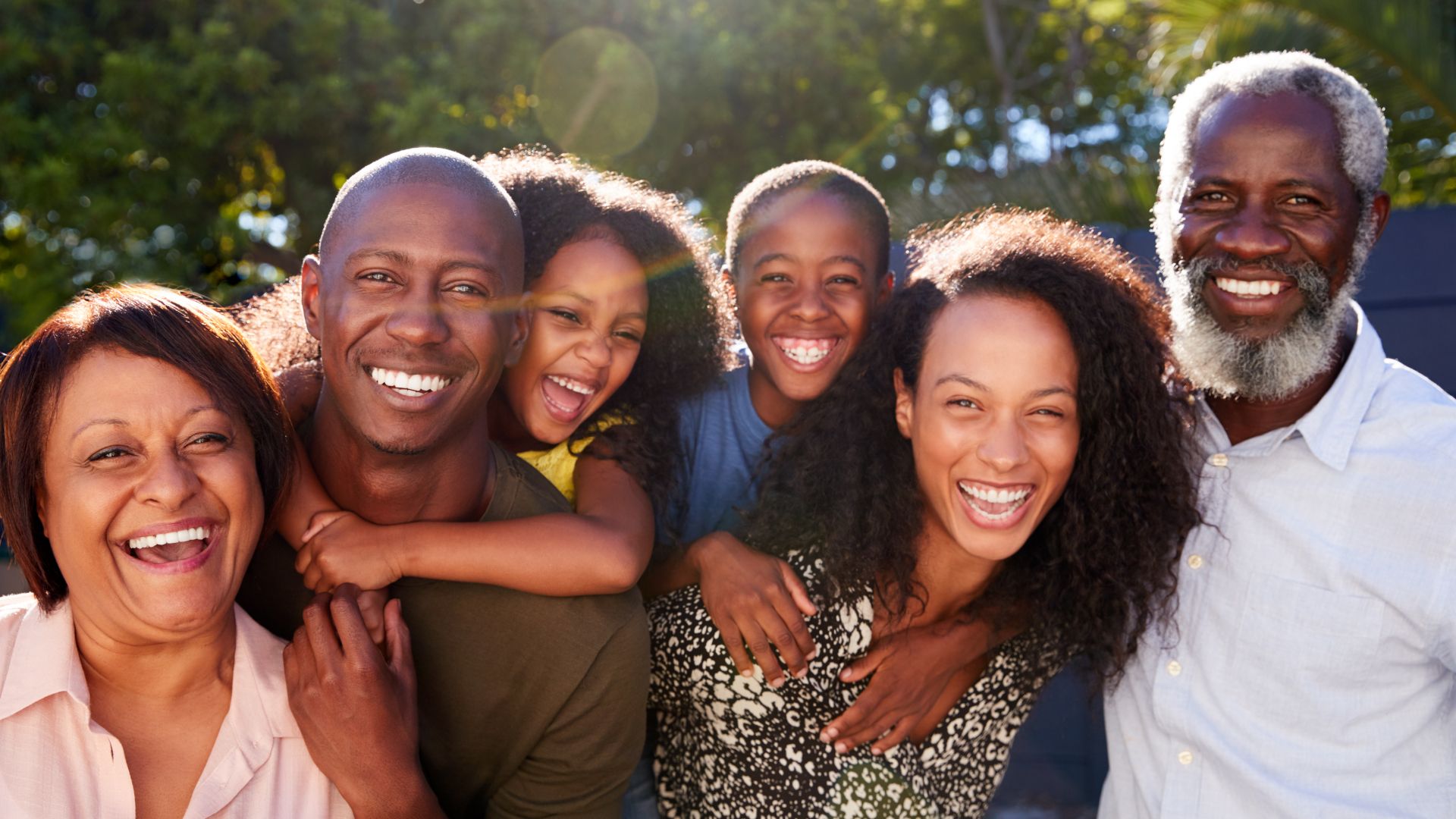 Multi-generational family outside in a park smiling at the camera