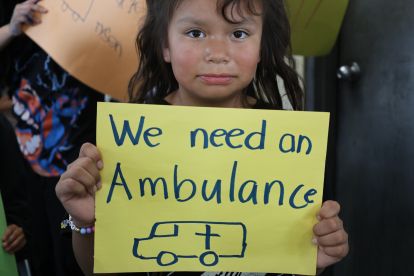 Un(e) jeune habitant(e) de Neskantaga tenant une pancarte indiquant, en anglais, « Nous avons besoin d’une ambulance »