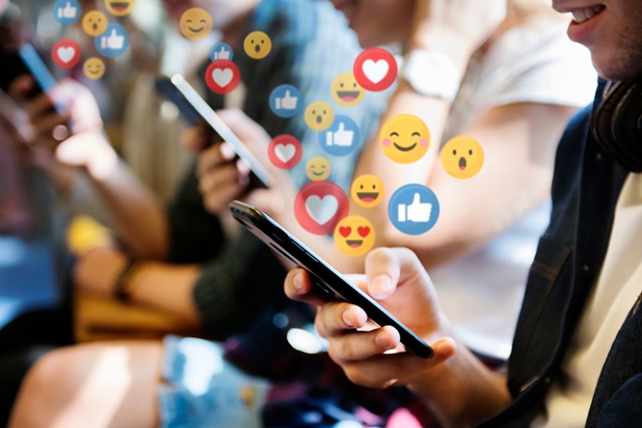 Different emoji such as happy faces, thumbs up, and hearts radiating from phone screens