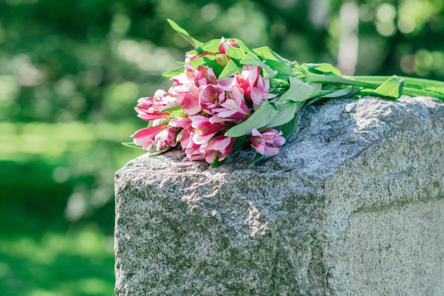 Tombstone with pink flowers resting on it