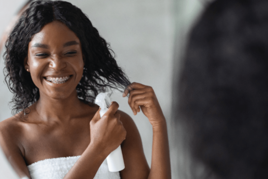 A person spraying their hair with a bottle.