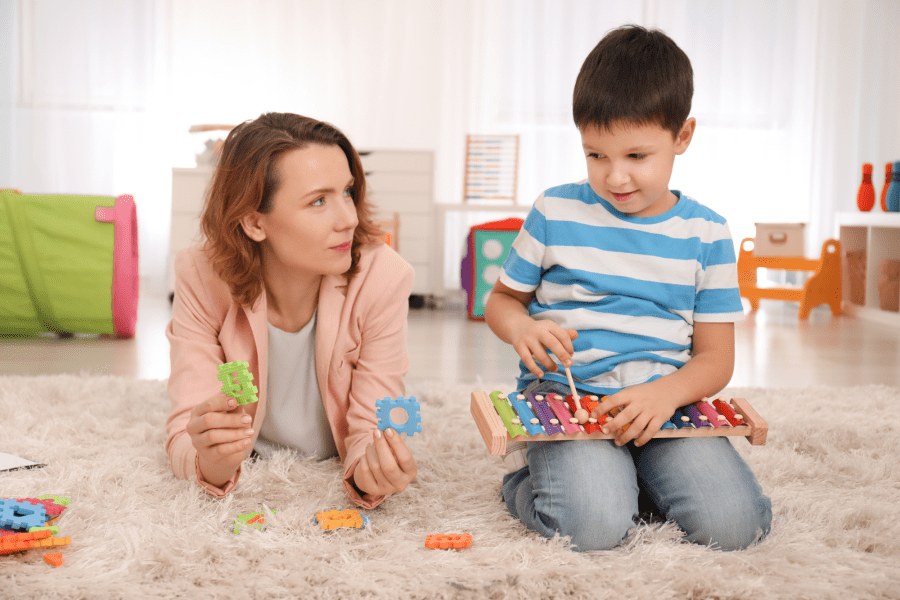 An adult and a child on the floor playing with toys.