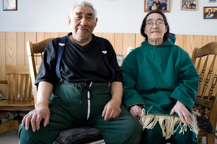 Older Indigenous couple sitting next to each other looking at the camera
