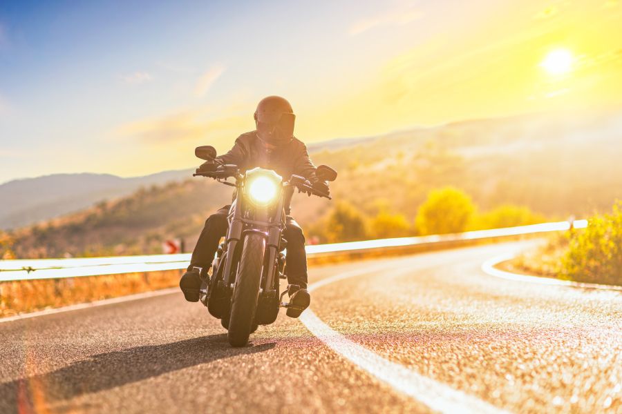 Motorcycle driving on a highway with a sunset behind it