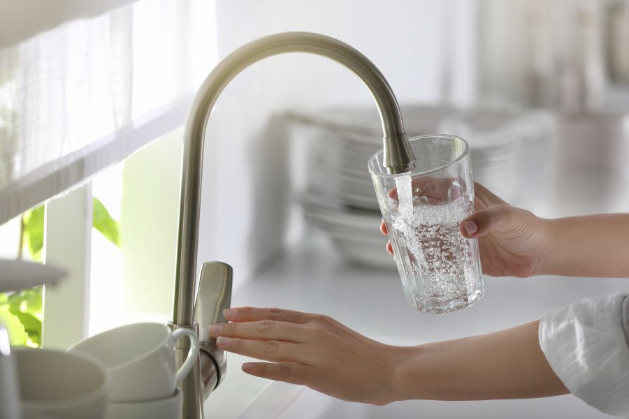 Person filling glass at kitchen sink