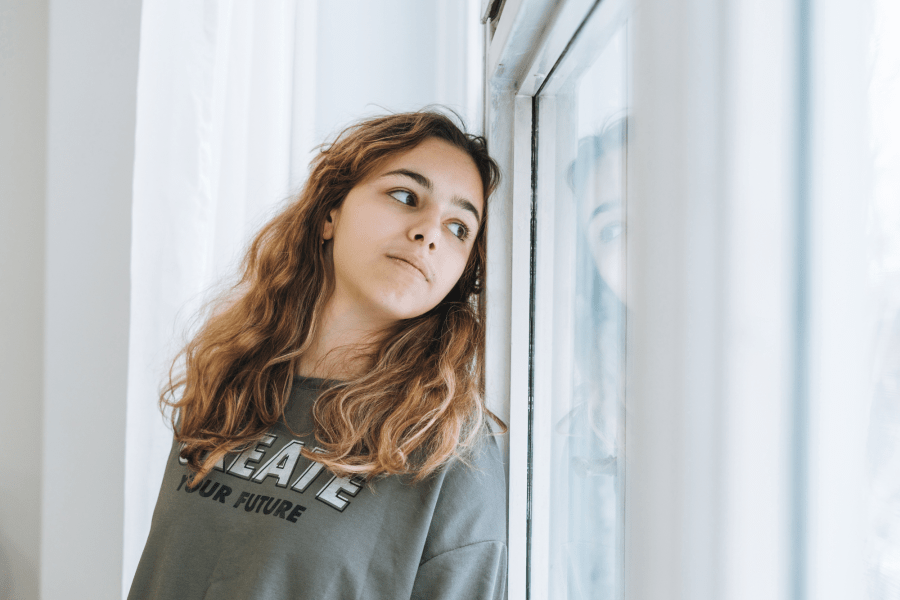 A young person looking out a window.