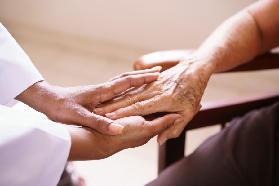 Two people, older and younger, clasping hands
