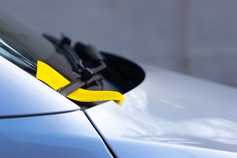 Yellow parking ticket on car windshield